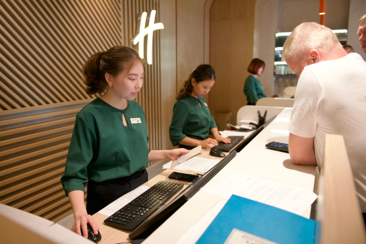 Команда Holiday Inn приветствует гостя в уютном лобби отеля: улыбка, чек-ин и профессионализм, Holiday Inn, гостеприимство, отель, сервис, путешествия Казахстан, лобби отеля, идеальный приём