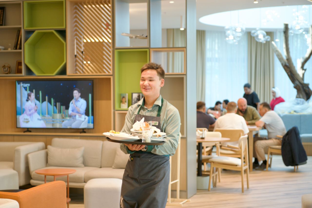Команда Holiday Inn приветствует гостя в уютном лобби отеля: улыбка, чек-ин и профессионализм, Holiday Inn, гостеприимство, отель, сервис, путешествия Казахстан, лобби отеля, идеальный приём