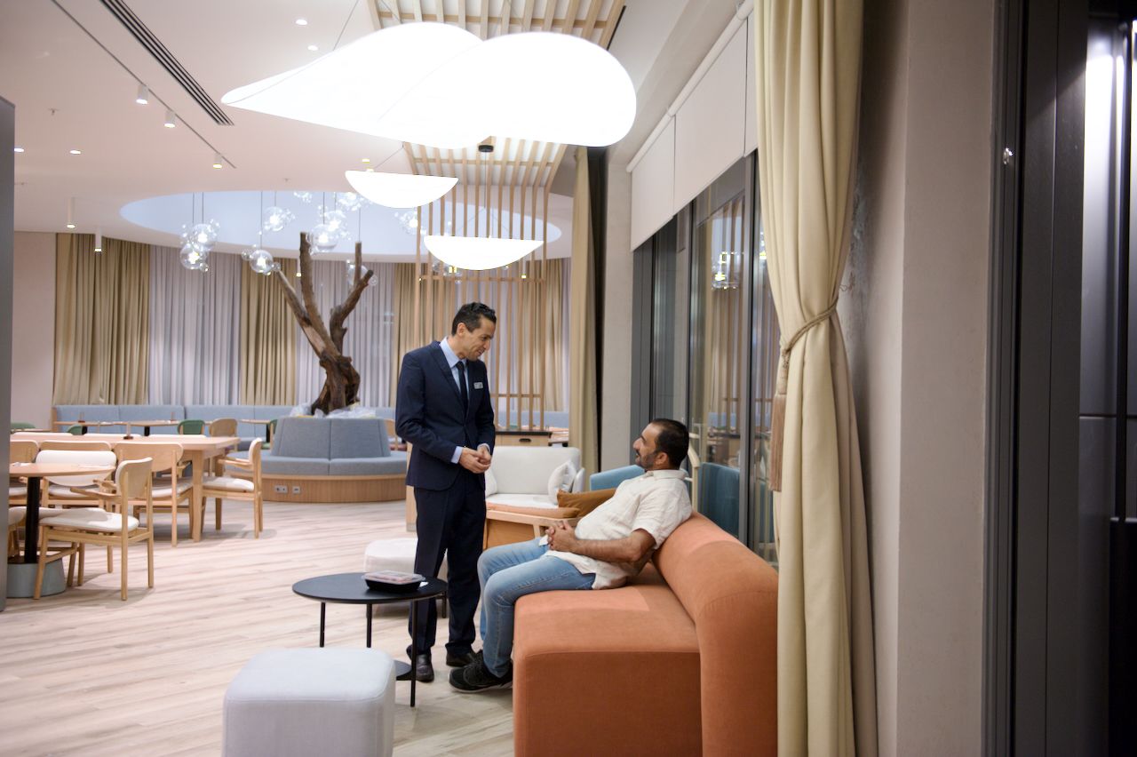 Команда Holiday Inn приветствует гостя в уютном лобби отеля: улыбка, чек-ин и профессионализм, Holiday Inn, гостеприимство, отель, сервис, путешествия Казахстан, лобби отеля, идеальный приём