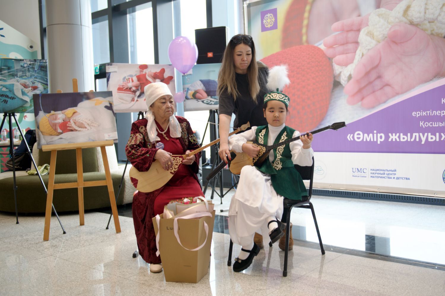 Қайырымдылық жобасының ашылуында Қазақстандағы Халықаралық волонтерлік жылын қолдауға арналған «Өмір жылуы» фотокөрмесінде Қосшы қаласындағы «28 ілмек» клубының қатысушылары мен қонақтары. «28 ілмек» клубы, Қосшы, Өмір жылуы, фотокөрме, волонтерлік, шала туған балалар, қайырымдылық, Қазақстан, Shanger.kz
