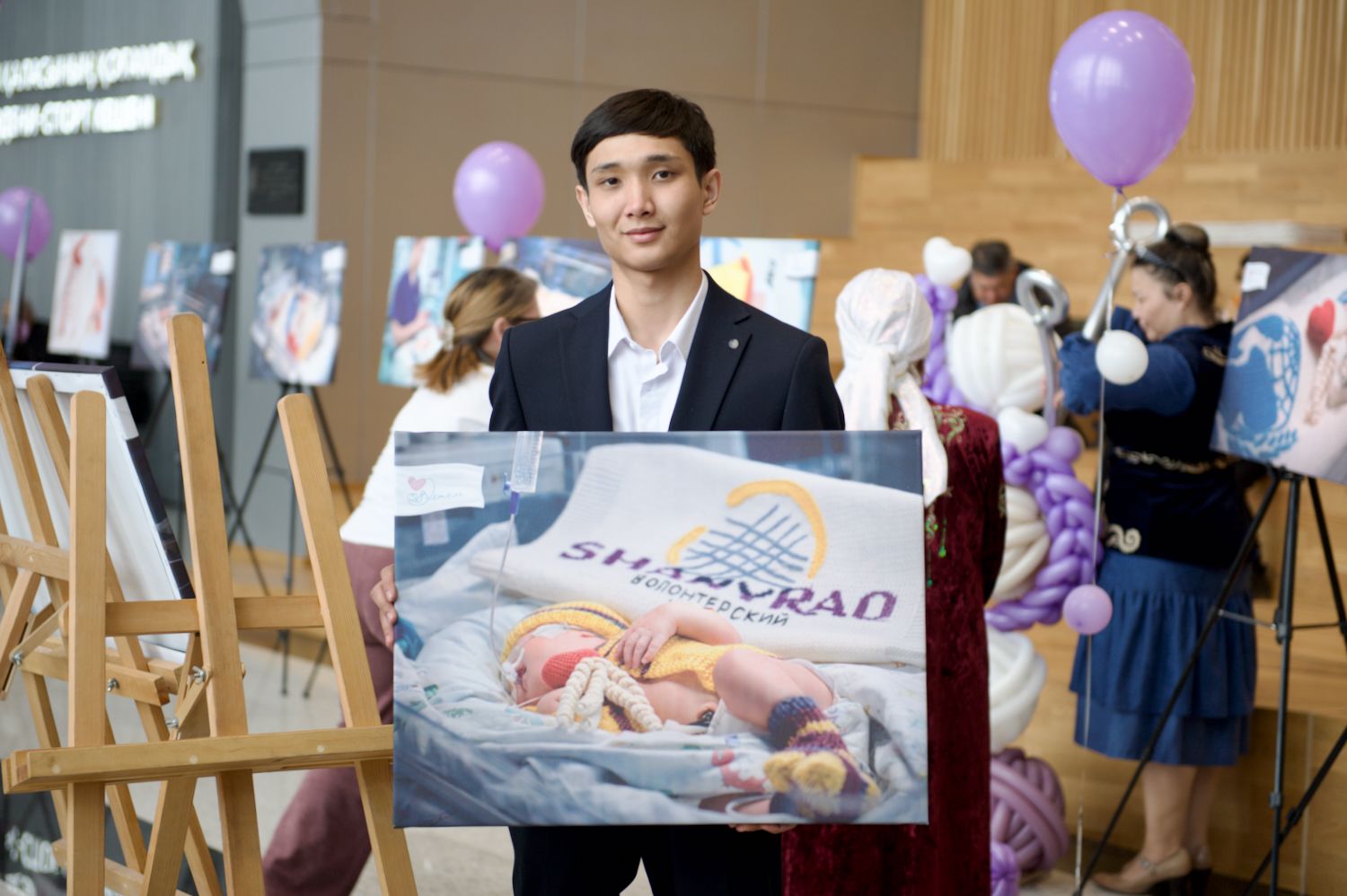 Қайырымдылық жобасының ашылуында Қазақстандағы Халықаралық волонтерлік жылын қолдауға арналған «Өмір жылуы» фотокөрмесінде Қосшы қаласындағы «28 ілмек» клубының қатысушылары мен қонақтары. «28 ілмек» клубы, Қосшы, Өмір жылуы, фотокөрме, волонтерлік, шала туған балалар, қайырымдылық, Қазақстан, Shanger.kz