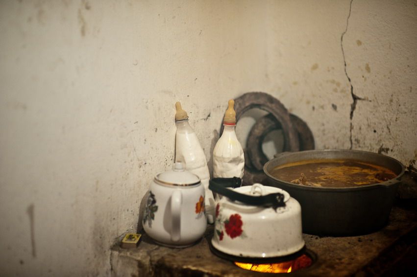 Кастрюля с мясным бульоном и чайник на старой печи в сельском доме Казахстана