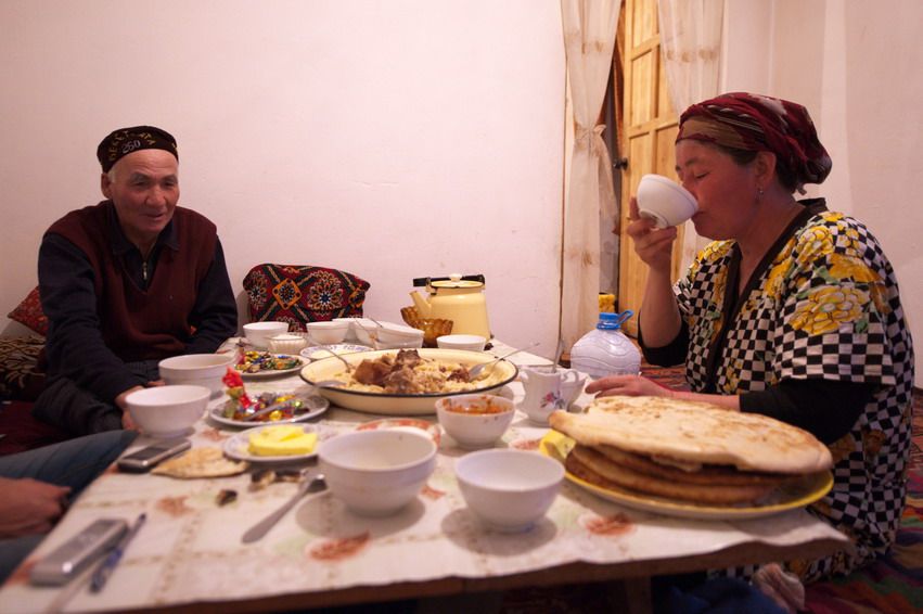 Мужчина и женщина за традиционным столом с чаем, лепёшками и бешбармаком после рабочего дня, семейный ужин, Казахстан, традиции
